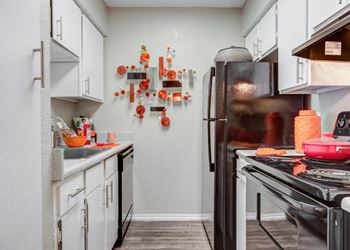 A kitchen with white cabinets and a stove and refrigerator